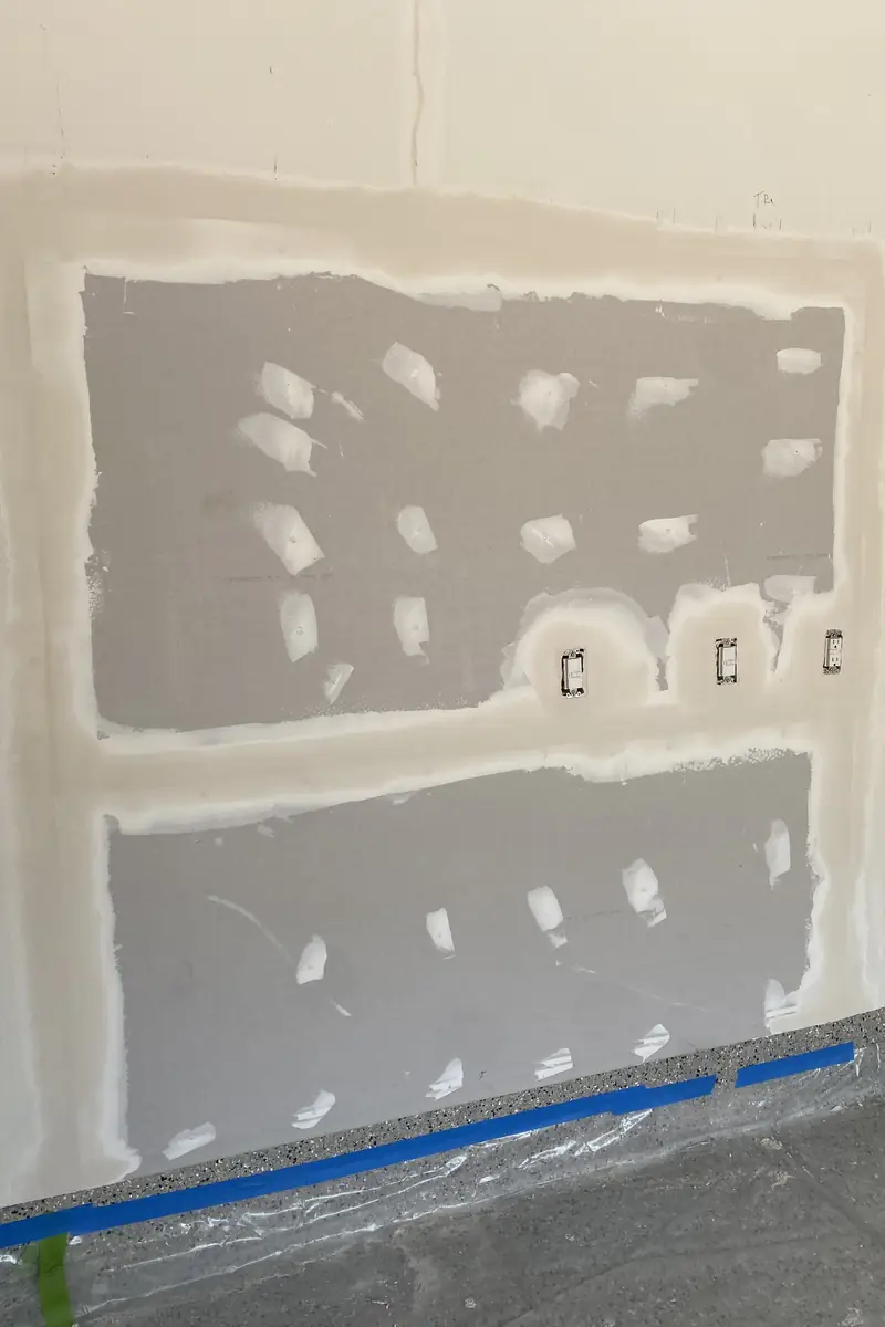 Patched drywall hole in living room, surface rebuilt smooth and blended, wall looks even without shadows or seams.