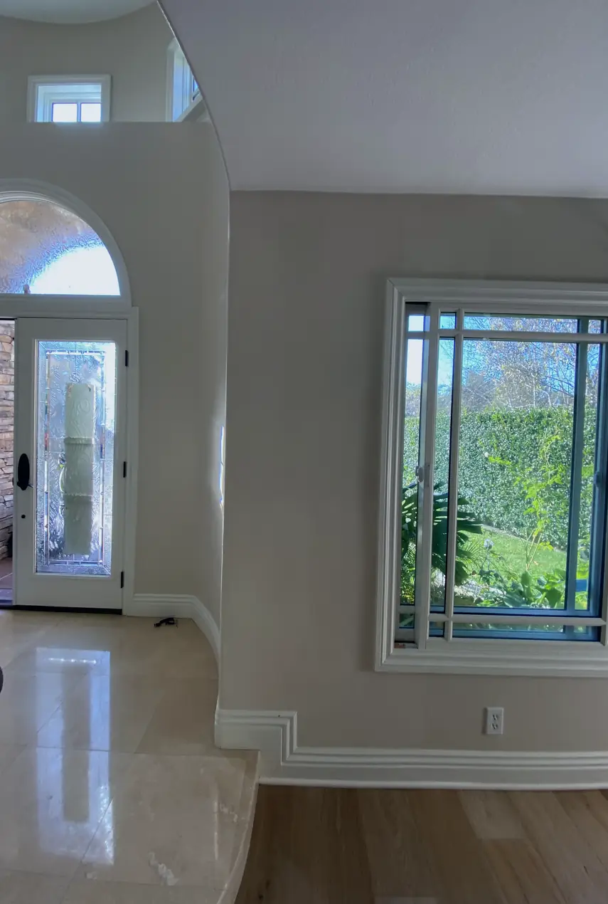 Repaired drywall patch where hole was rebuilt and skimmed smooth, wall now flat and even with no visible seams or shadows.