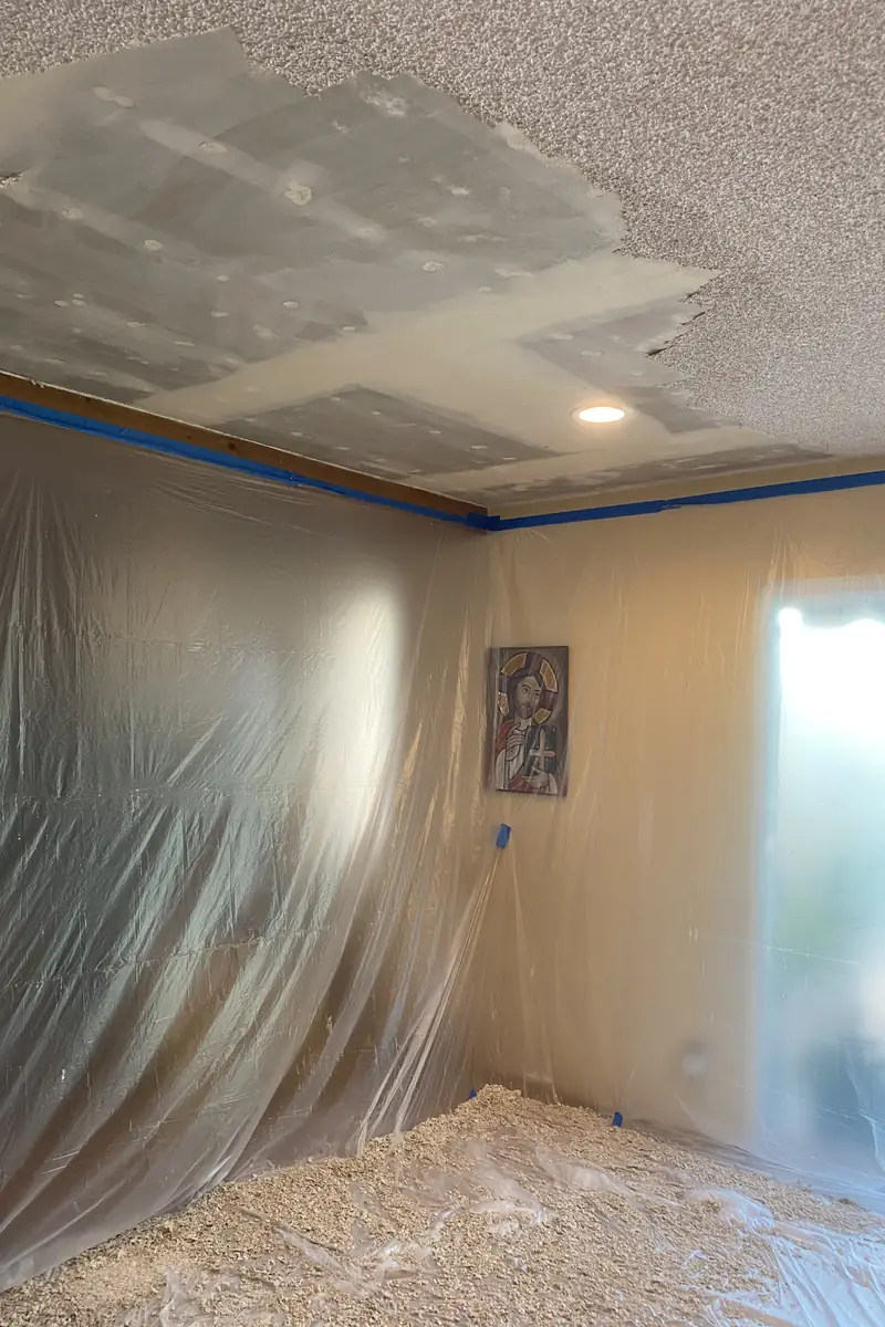 Patched drywall hole skillfully rebuilt and skimed for a smooth, flat wall surface with even natural light and no visible seams.